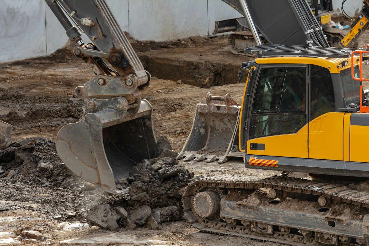 Een graafmachine schept grond en stenen